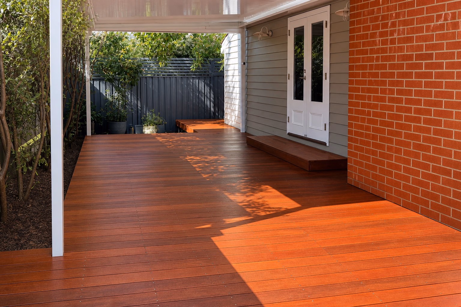 A finished hardwood deck beside a brick column and weatherboard wall