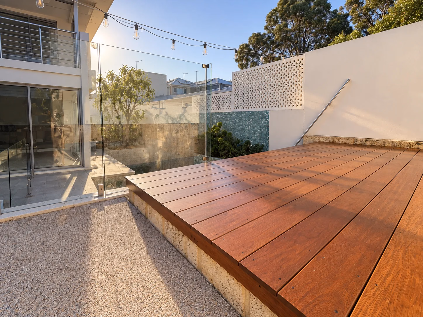 Completed oiled hardwood deck with a frameless glass balustrade in a rendered courtyard