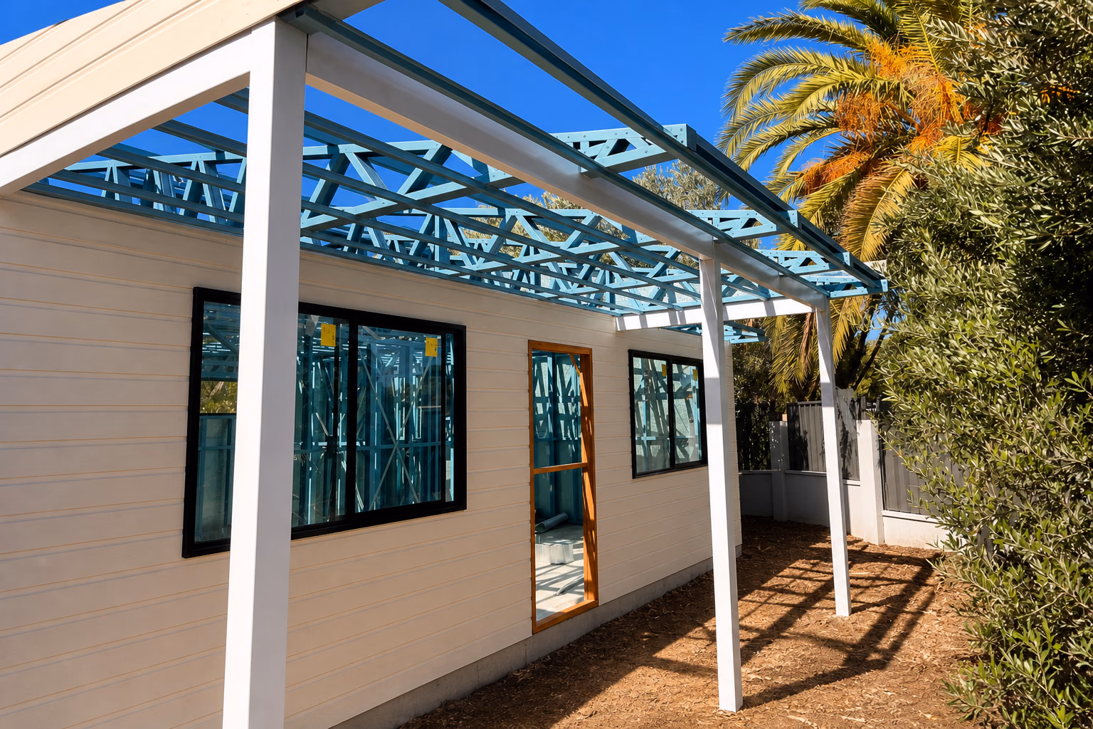 A granny flat porch with cream cladding and blue steel roof trusses