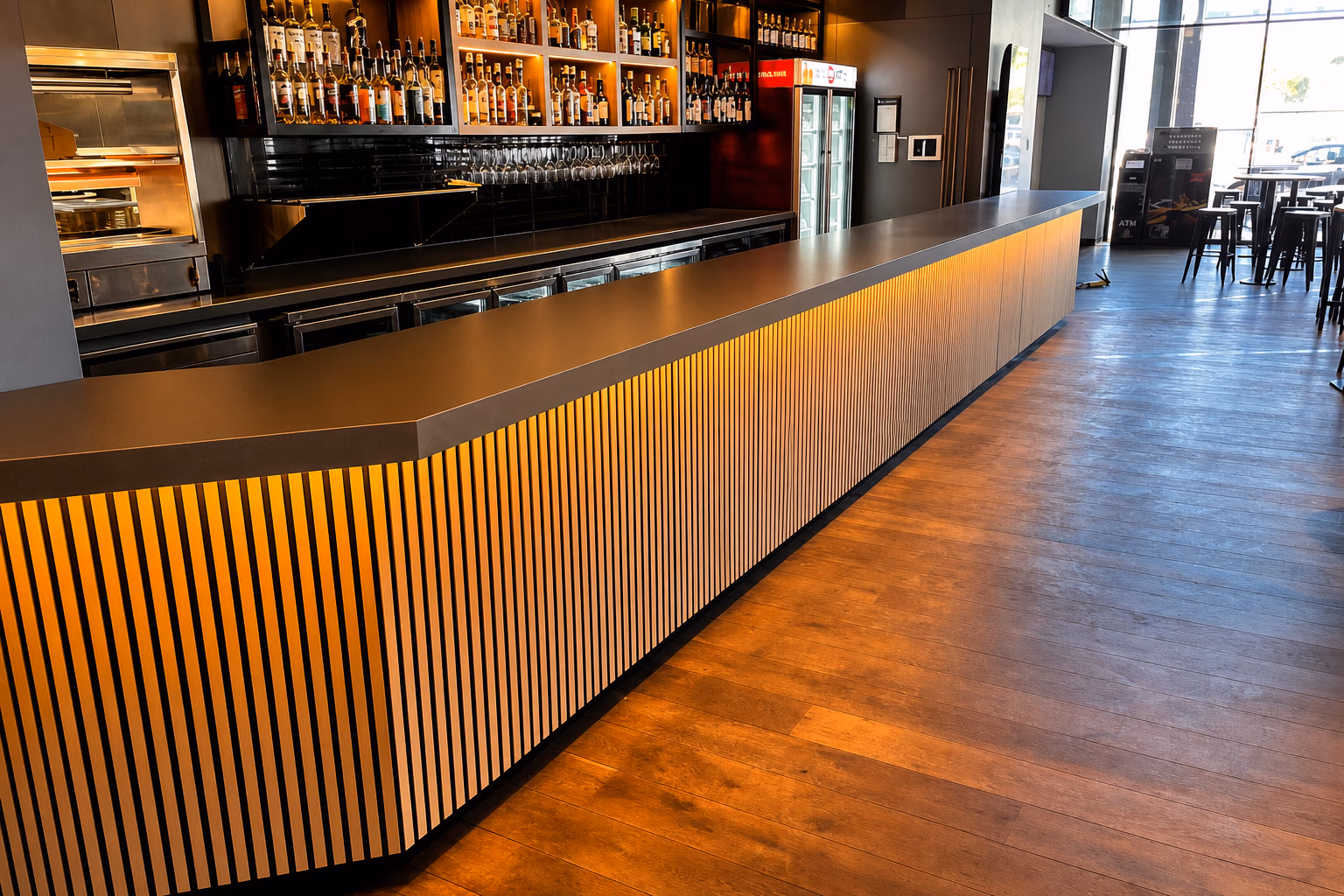 Vertical wood slats on a commercial bar with diagonal wide-plank hardwood