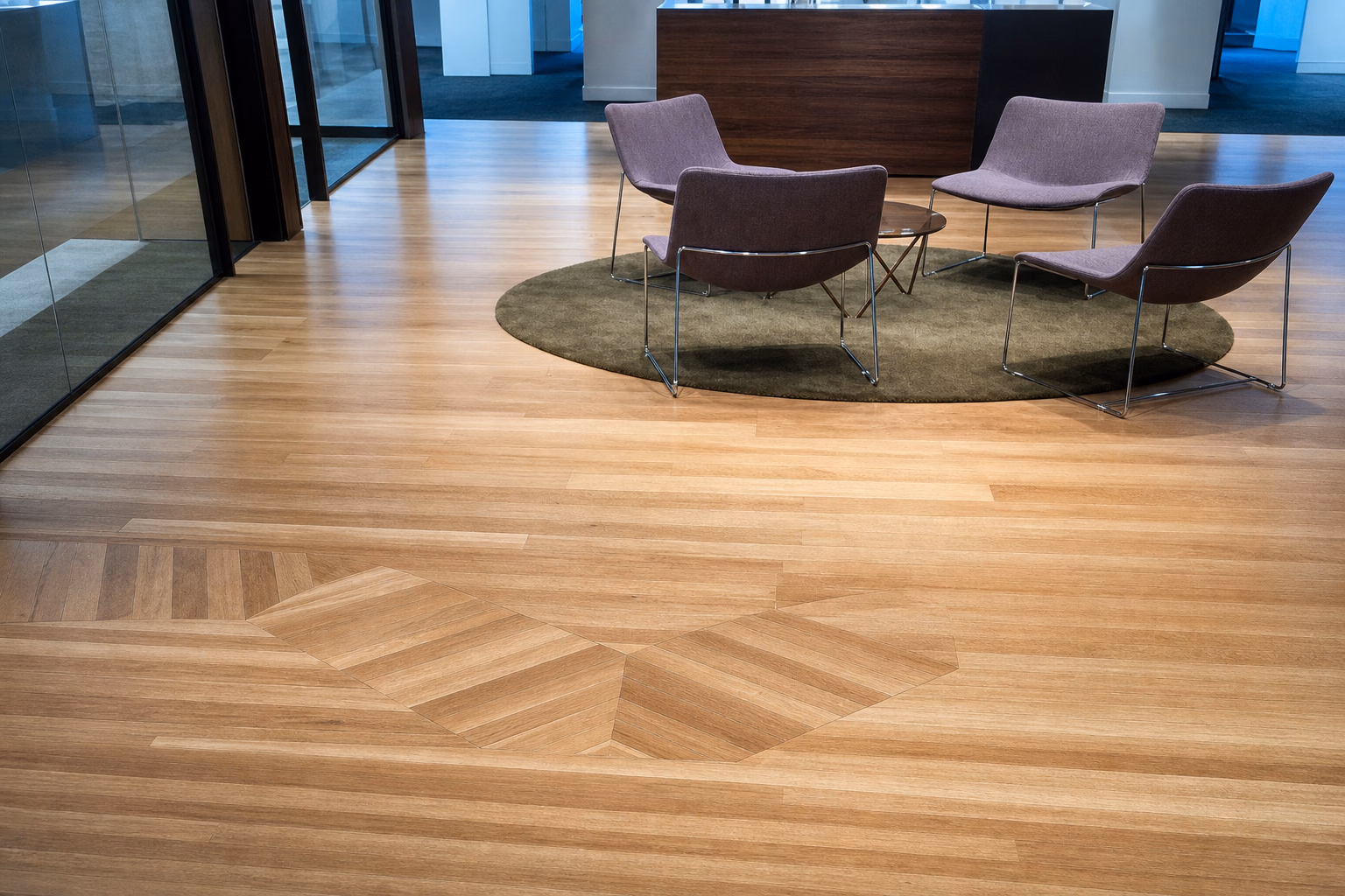 A light hardwood floor with a nested chevron geometric inlay in a commercial lobby